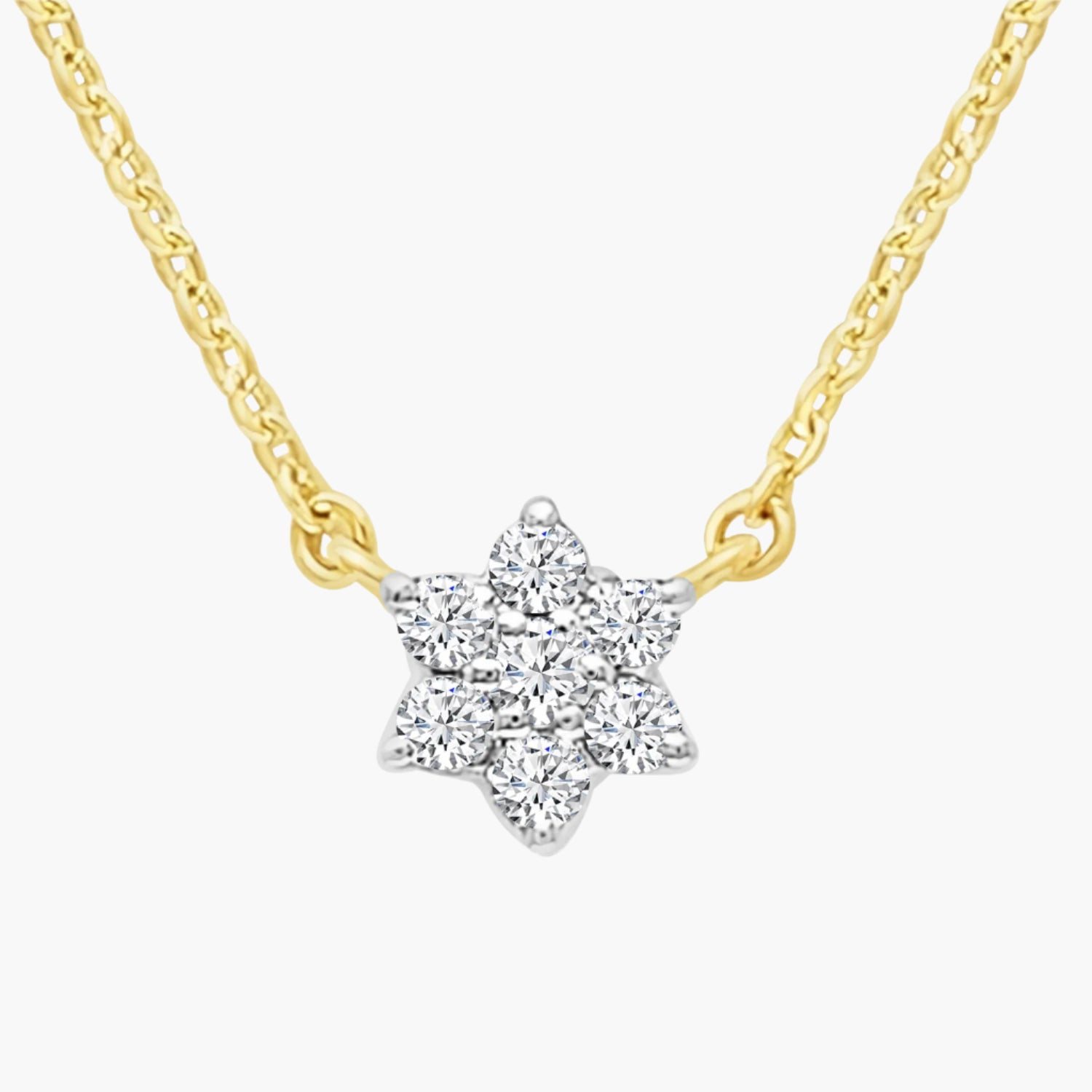 Star-shaped diamond pendant on a gold chain against a white background