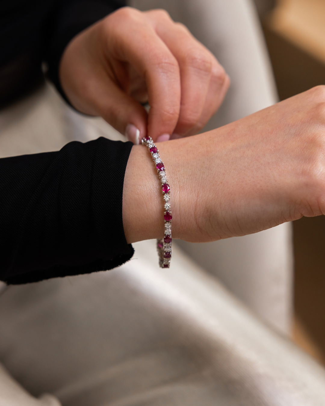 Close-up of a person wearing a bracelet with red stones on a blurred background
